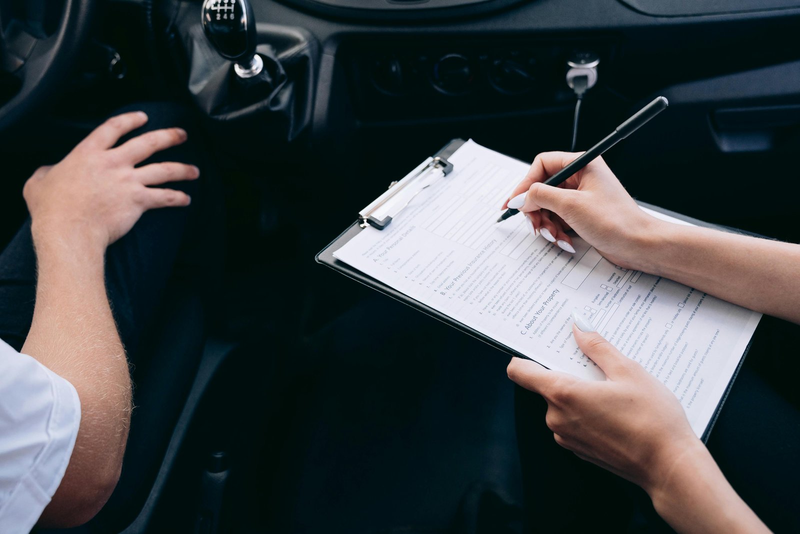A car dashboard with an insurance policy document and car keys, symbolizing car insurance decisions.