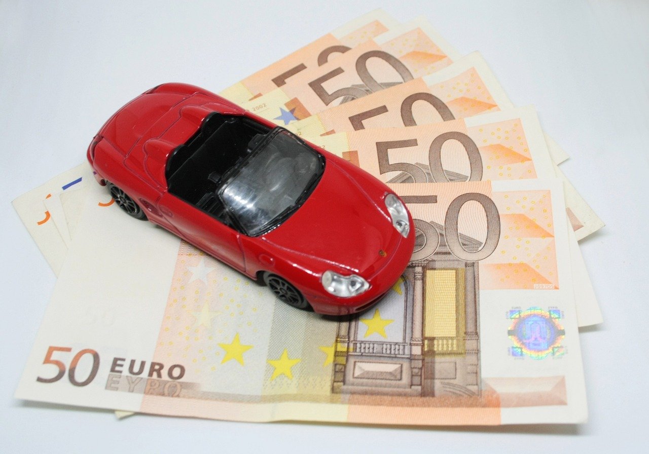 A red toy car on top of coins, symbolizing savings on Whale Maven Auto insurance.