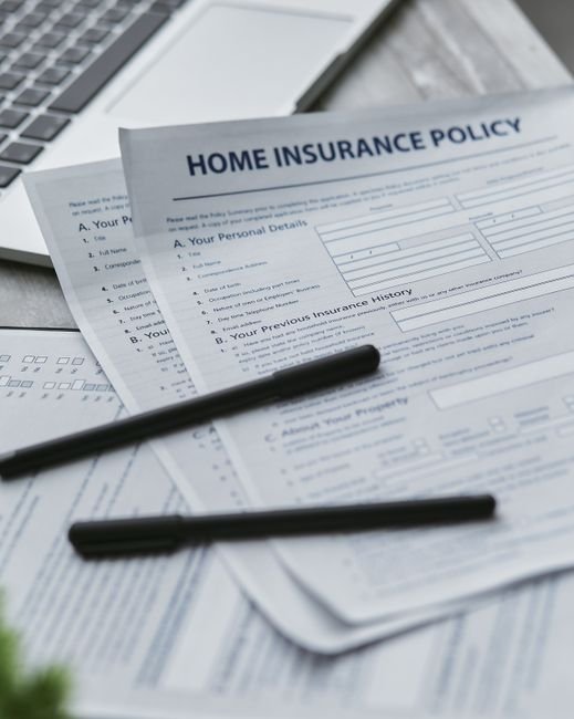 bankrate home insurance rates - Close-up of home insurance documents with a laptop for financial planning.