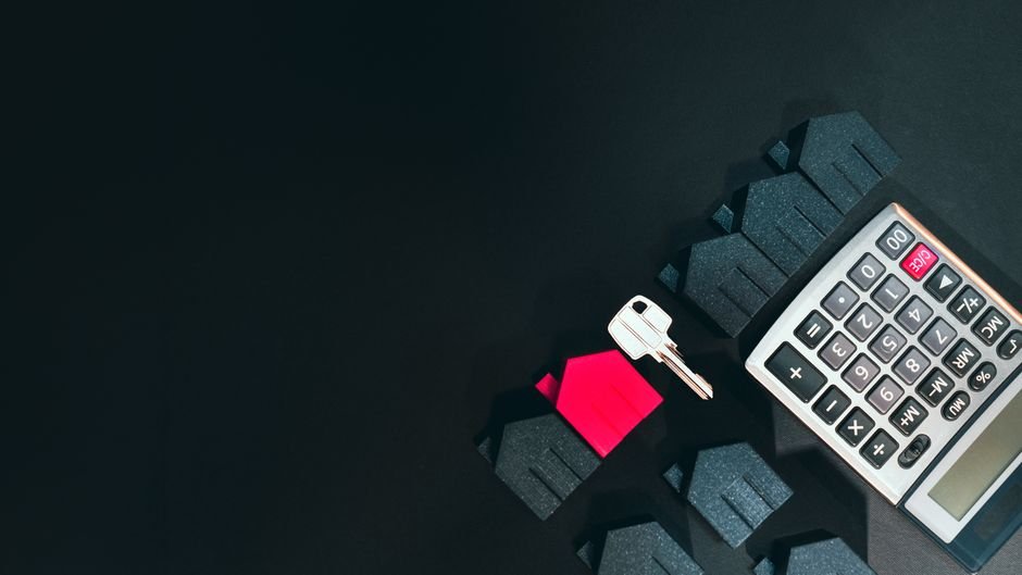 bankrate home insurance rates - Real estate concept image featuring a calculator, houses, and a key on a black background.