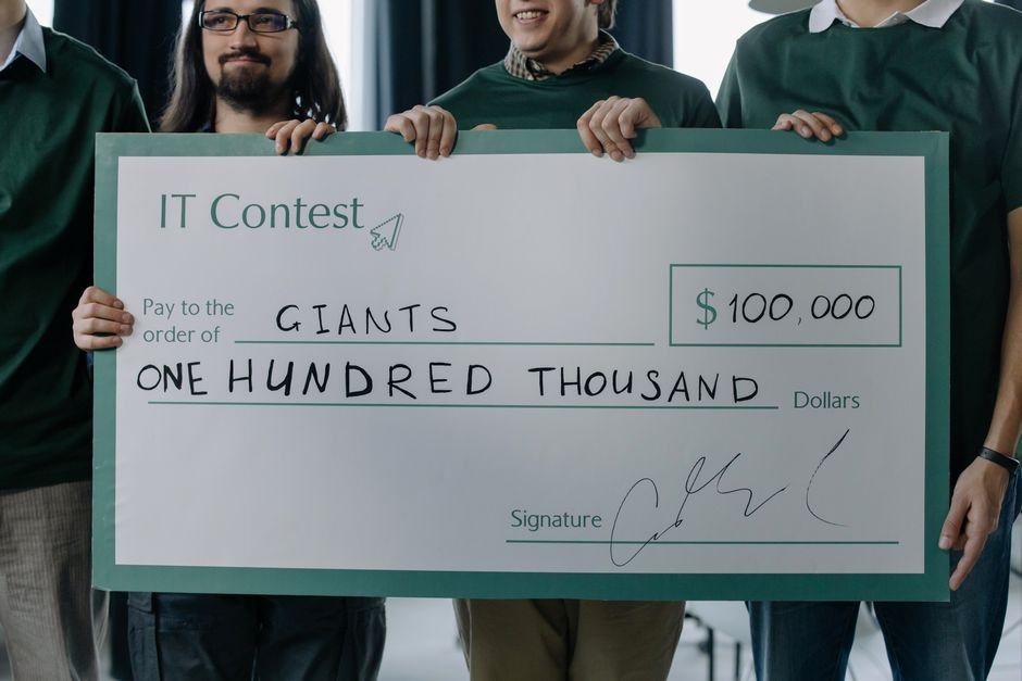 trendndaily win a $500 cash prize - Group of men holding a $100,000 prize check after winning an IT contest.